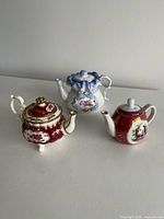 Front view of three miniature porcelain teapots