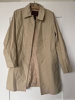 Front view of beige Coach trench coat hanging