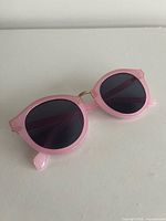 Front view showing round pink frame and dark lenses