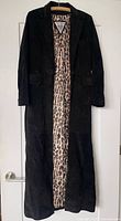 Front view of full-length black leather coat on hanger