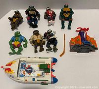 Group shot showing all nine figures, two vehicles, and loose hockey stick