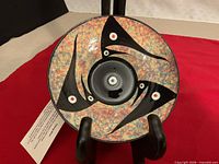 Front view of signed handmade ceramic talking bowl showing multicoloured glaze and black abstract motif