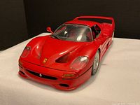 Front three-quarter view of red Ferrari F50 model car showing nose badge, headlights, windshield, wheels