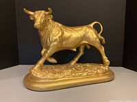 Front view of gold bull statue on oval base