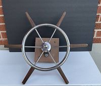Front view of stainless and wood ship wheel on plywood mount