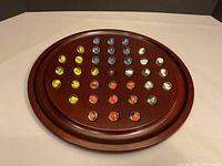 top view of loaded wood solitaire board with marbles in play positions
