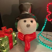 Snowman face with gift box beside, present lights on