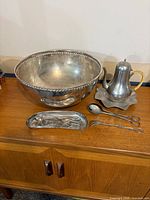 All seven silver-plate pieces grouped on cabinet