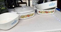 Three CorningWare dishes and glass lid on table