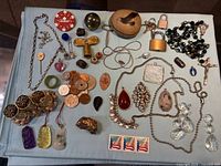 Full layout of mixed jewelry, coins, padlocks, carved pendants on blue cloth