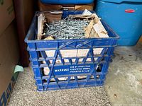 Milk crate containing large quantity of nails in torn box