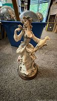 Full view of figurine front, detached wood base visible