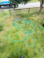 Full view of coiled green garden hose on grass
