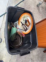 Mixed cookware and dinnerware inside storage bin
