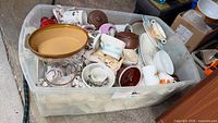Overall view of plastic tote containing assorted dishware pieces