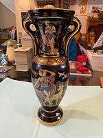 Full view of black ceramic vase showing Greek figural designs and twin handles