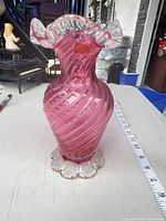 Front view showing pink swirl body, ruffled clear rim, scalloped clear foot