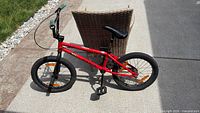 Full side view showing red Radio BMX bike, wheel size, pegs, kickstand