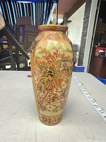 Full front view of vase showing painted geisha scene and tape measure for scale