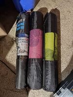 Three rolled yoga mats in mesh carry bags