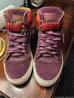 Front view of both sneakers showing uppers, laces, buckle strap, brand tag
