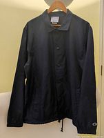 Front view of navy Champion windbreaker hanging