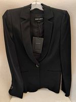 Front view of black Giorgio Armani blazer on hanger showing single button and lapel