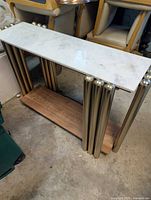 Full view of console table showing marble top, brass legs, wood shelf