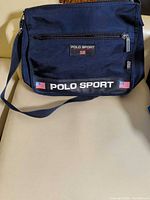 Front view showing Polo Sport logo, front zip pocket, flap, adjustable strap