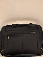 Front view of Samsonite black laptop bag showing logo, front pocket, handles