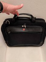 Front view of Swissgear black laptop briefcase showing logo, front pocket, carry handles