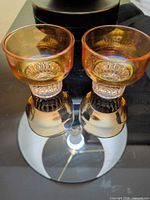 Pair of amber iridescent cordial glasses upright showing bowl, stem and base reflection