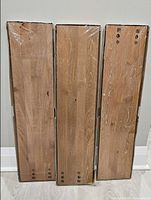 Front view of three sealed wooden shelves showing grain and hardware holes