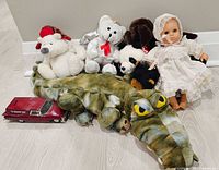 Group shot of all stuffed animals, doll, and car bank