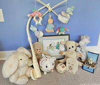 Group shot of entire lot against blue wall showing mobile, framed print, plush animals, banks, piggy bank and music box