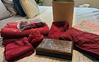 All items grouped on bed showing towels, quilt, waste basket, pouf, potpourri, decorative box