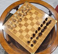 angled view of complete chess set on glass table