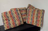 Four multicolour square patterned throw pillows grouped on surface