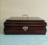 Closed dark wood jewelry box showing brass handle and clasp