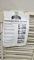 Front view of expandable metal pet gate with instruction sheet