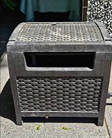 Front view of Suncast hose caddy showing wicker design and hose guide opening