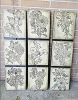 Front view of three vertical plaques showing floral line art designs