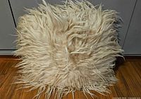 Front view of one square Icelandic sheepskin pillow with long cream wool