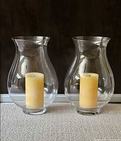 both glass hurricane holders with candles front view