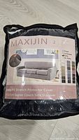 Front of packaged Maxijin stretch sofa slipcover showing brand, color swatches, product image