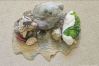 Full view of textile sculpture showing multiple fabric rocks, shells and wavy base