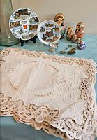 Overview with lace placemats, souvenir plates, Matryoshka dolls, pewter cup, spoons