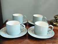 Four matching blue-grey espresso cups on saucers