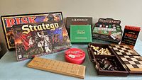 All games laid out on table showing variety of board and card games, wooden chess set and cribbage board