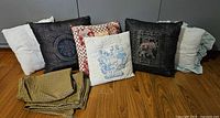 Group of six cushions and two folded pillow covers displayed on floor